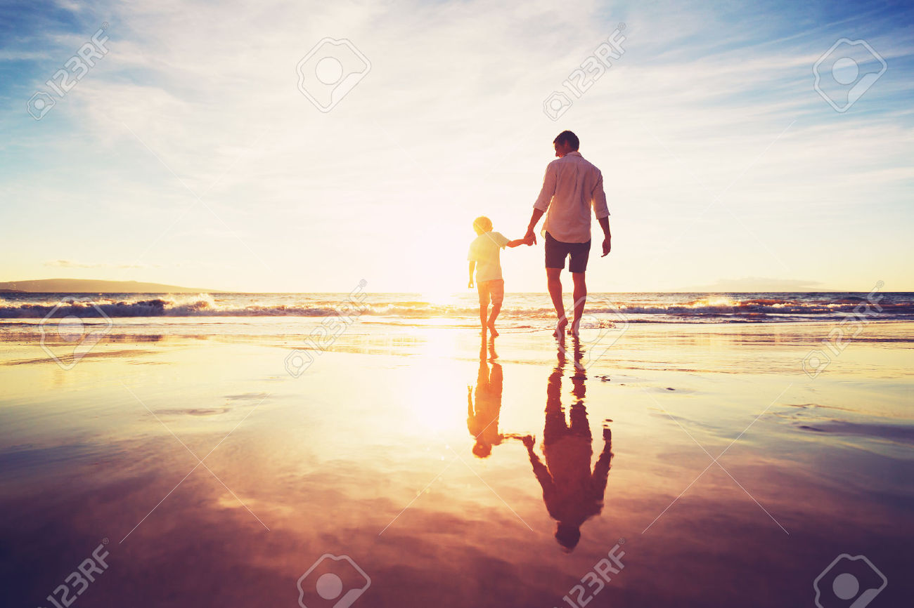 48345262-Padre-e-hijo-Agarrados-de-la-mano-caminando-juntos-en-la-playa-al-atardecer-Foto-de-archivo